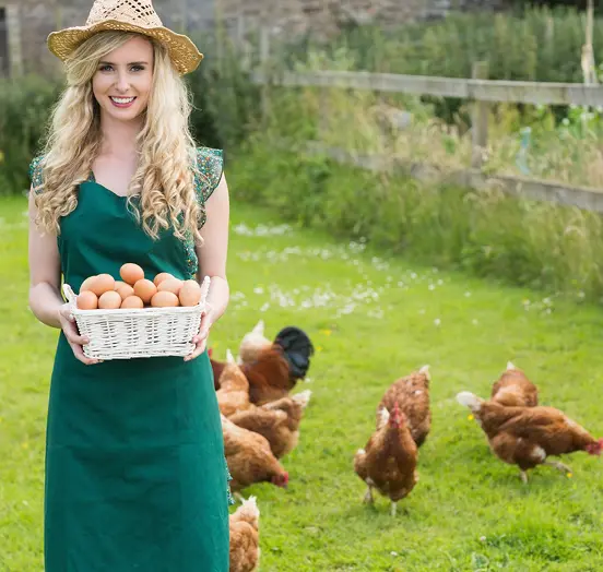 Woman holding eggs near chickens